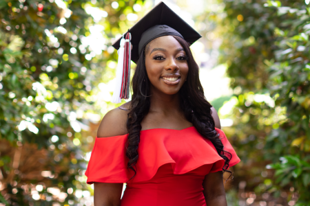 Danielle Obiri poses in a red dress with her graduation cap